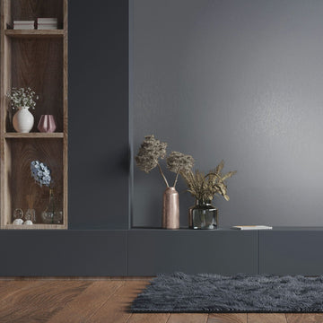 Marburg Naomi 82537 Gray wallpaper with a fine vertical texture behind a dark built-in console and wooden shelf. Two vases with dried plants sit on the console, with books and small decor on the shelf and a shag rug on a wood floor in front.