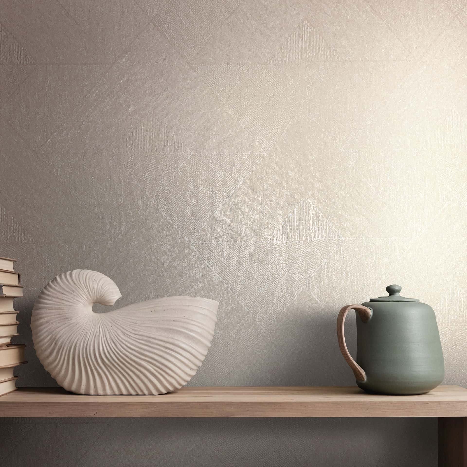 Marburg Naomi 82546 Beige wallpaper with a subtle textured geometric pattern behind a shelf styled with a shell-shaped sculpture, a stack of books, and a teapot.