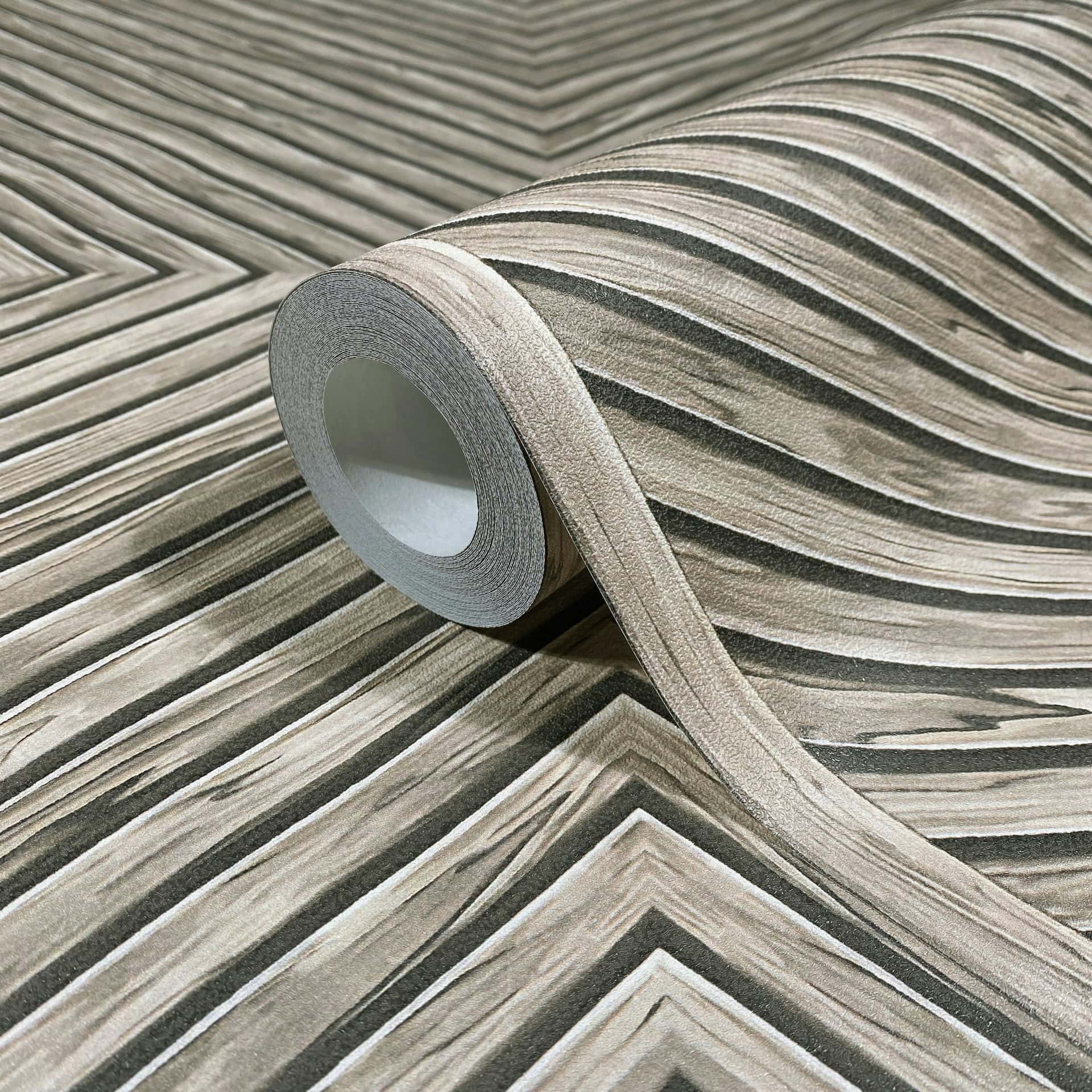 Marburg Naomi 89018 Close-up of a wallpaper roll resting on matching beige and gray chevron woodgrain pattern.