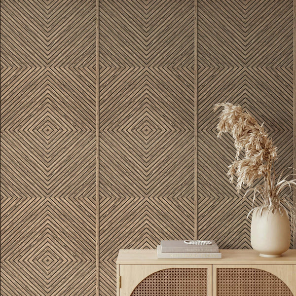 Marburg Naomi 89019 Beige geometric wallpaper with diagonal lines forming nested diamonds, shown behind a light wood console with stacked books and a ceramic vase of dried grasses.