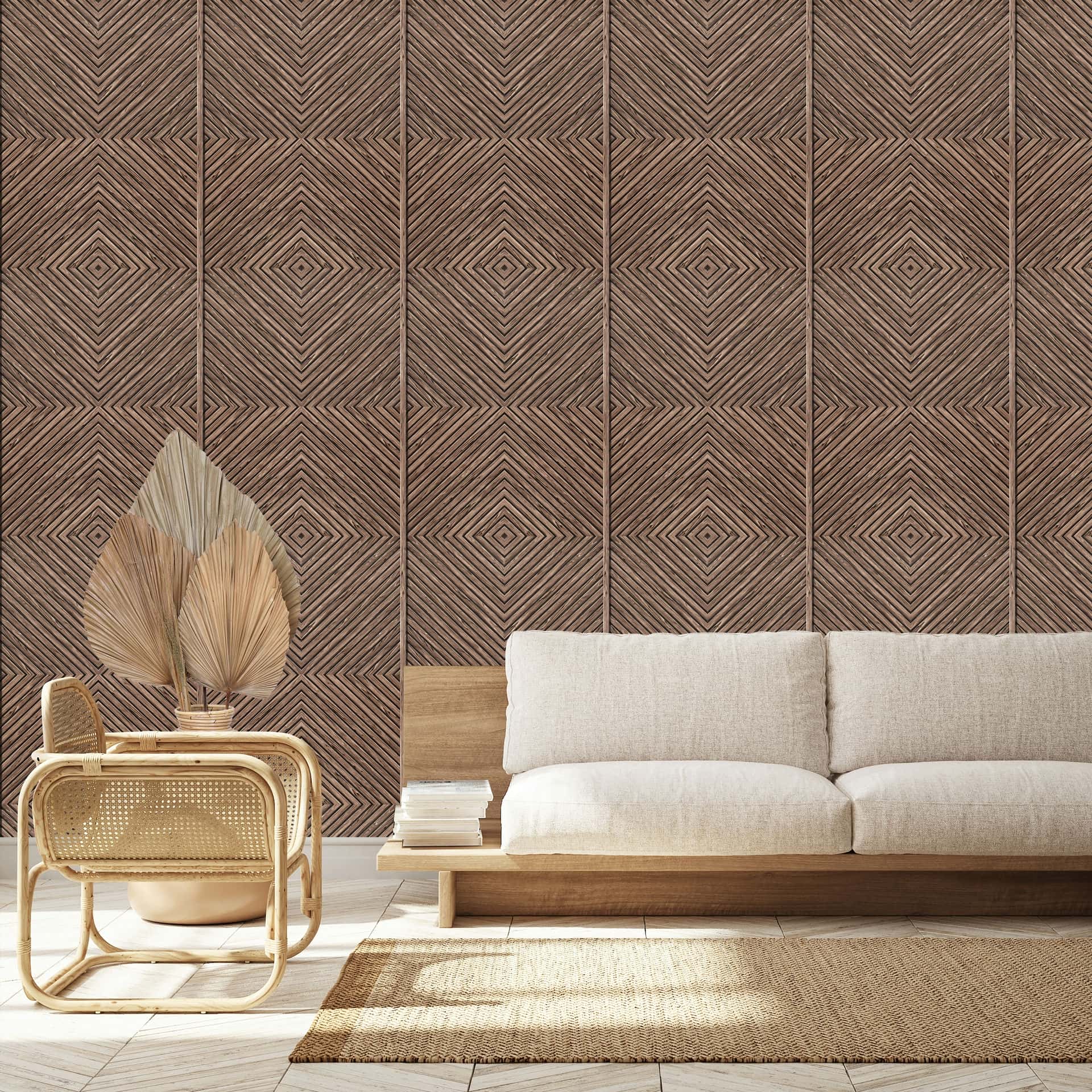 Marburg Naomi 89020 Brown geometric diamond-line wallpaper creates a feature wall behind a light upholstered sofa, a rattan chair, a small table holding dried palm leaves in a pot, a woven rug, and a stack of books.
