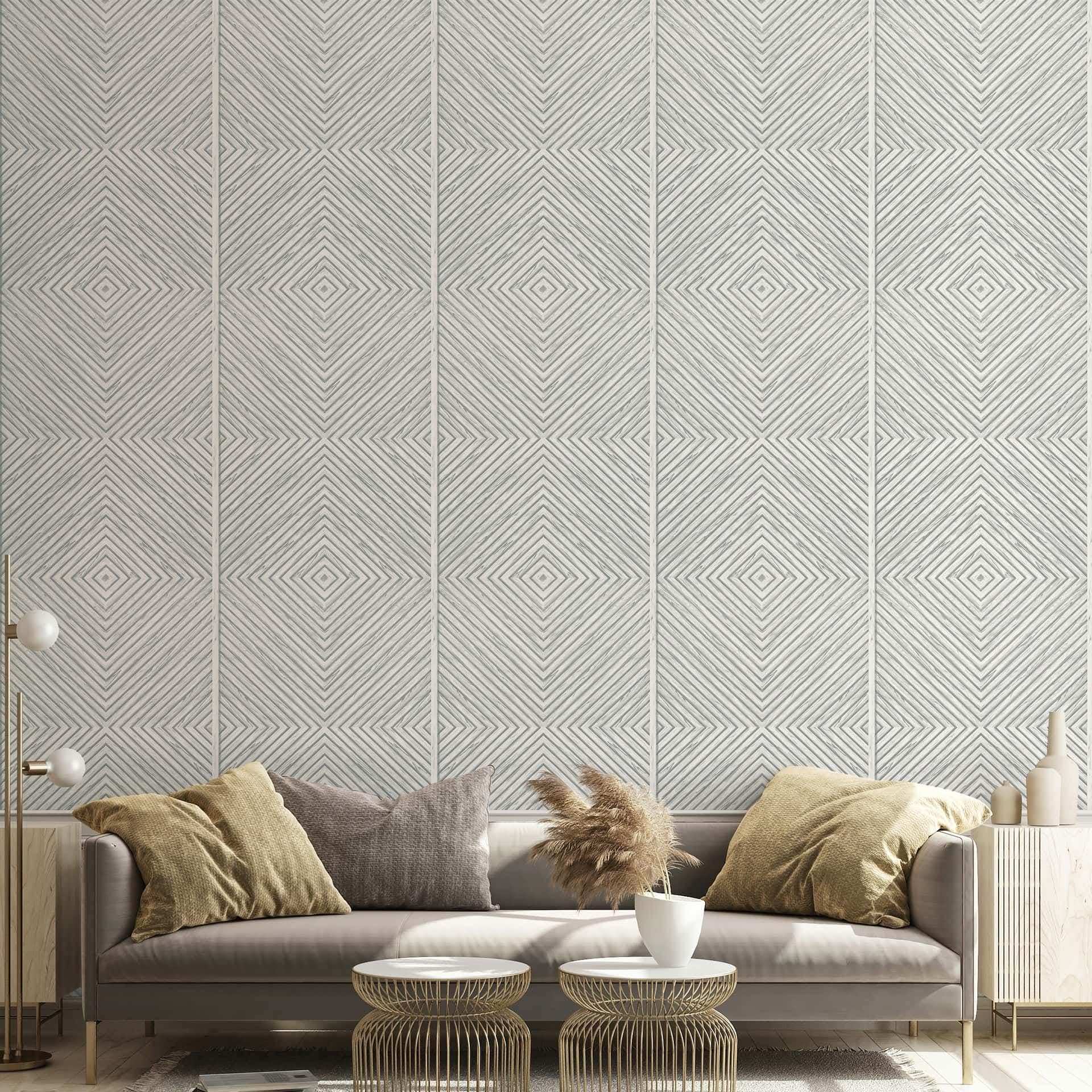 Marburg Naomi 89021 Gray-and-white wallpaper with repeating concentric diamond line squares behind a living room setup with a sofa, two round metal coffee tables, a globe floor lamp, a small planter with dried grass, and vases on a side cabinet.