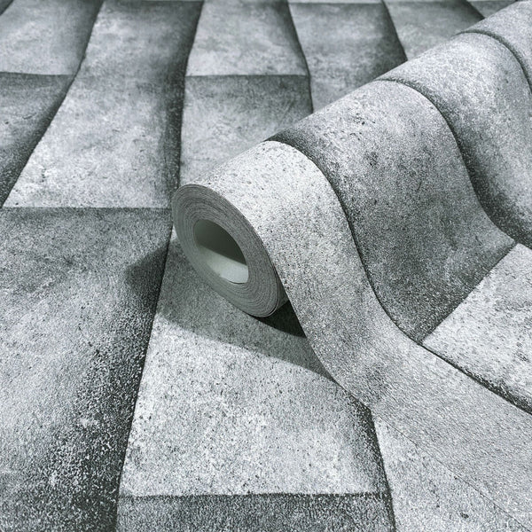 Marburg Novamur Mona 81649 Product photo of a wallpaper roll resting on the same design, showing a gray textured geometric block pattern with a shaded 3D effect.