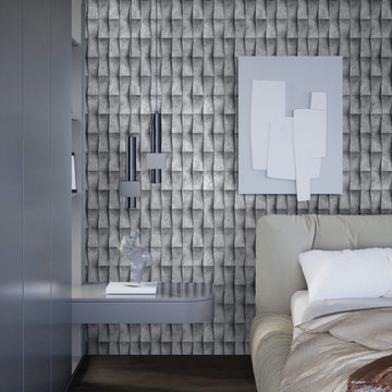 Marburg Novamur Mona 81649 Bedroom scene featuring gray 3D-effect geometric wallpaper behind a bed, with two chrome pendant lights, a floating shelf holding a small sculpture and book, and abstract wall art.