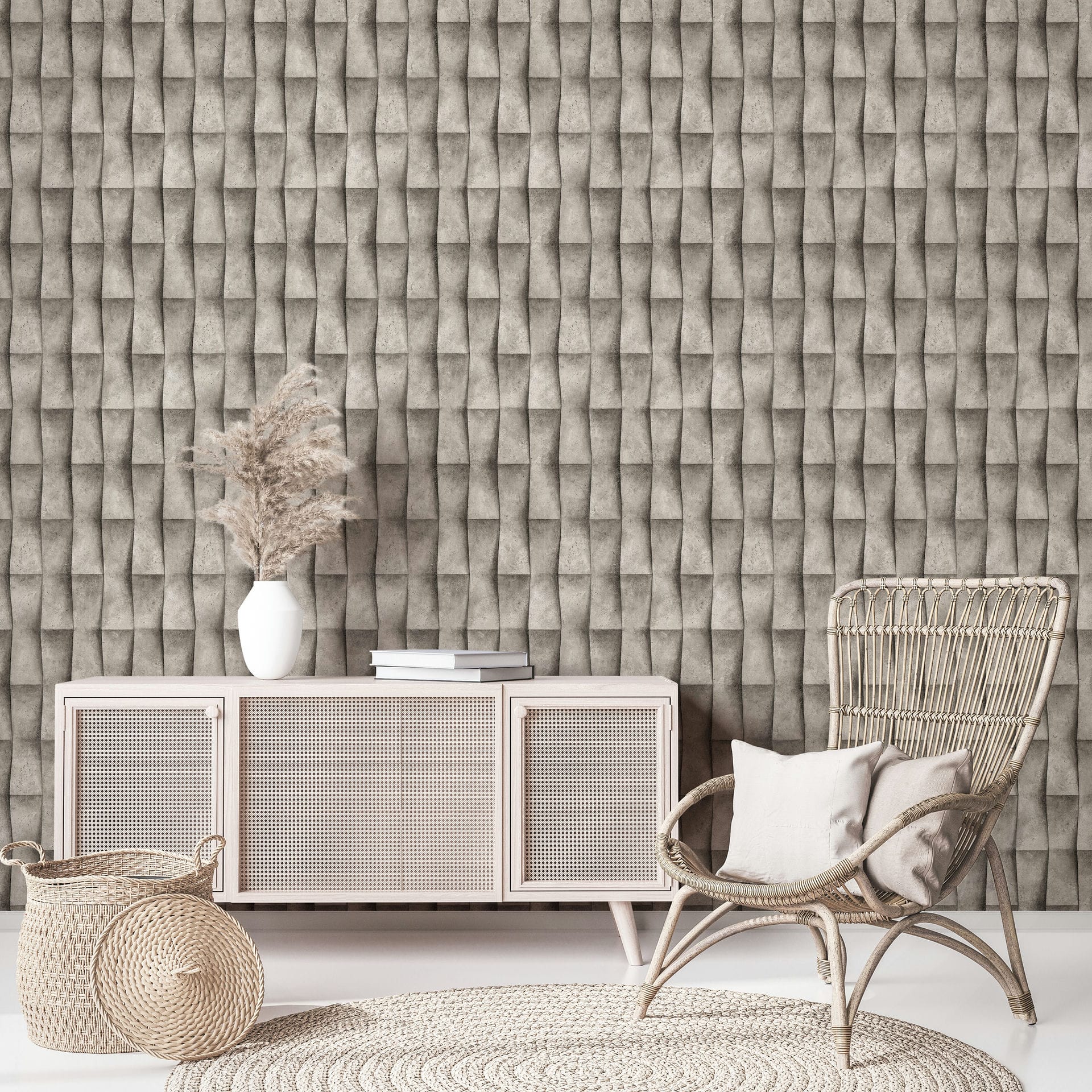 Marburg Novamur Mona 81650 Beige‑grey geometric wallpaper with a 3D folded effect behind a light cane-front sideboard, a white vase with dried grasses and books, a rattan chair with cushions, a woven basket, and a round braided rug.