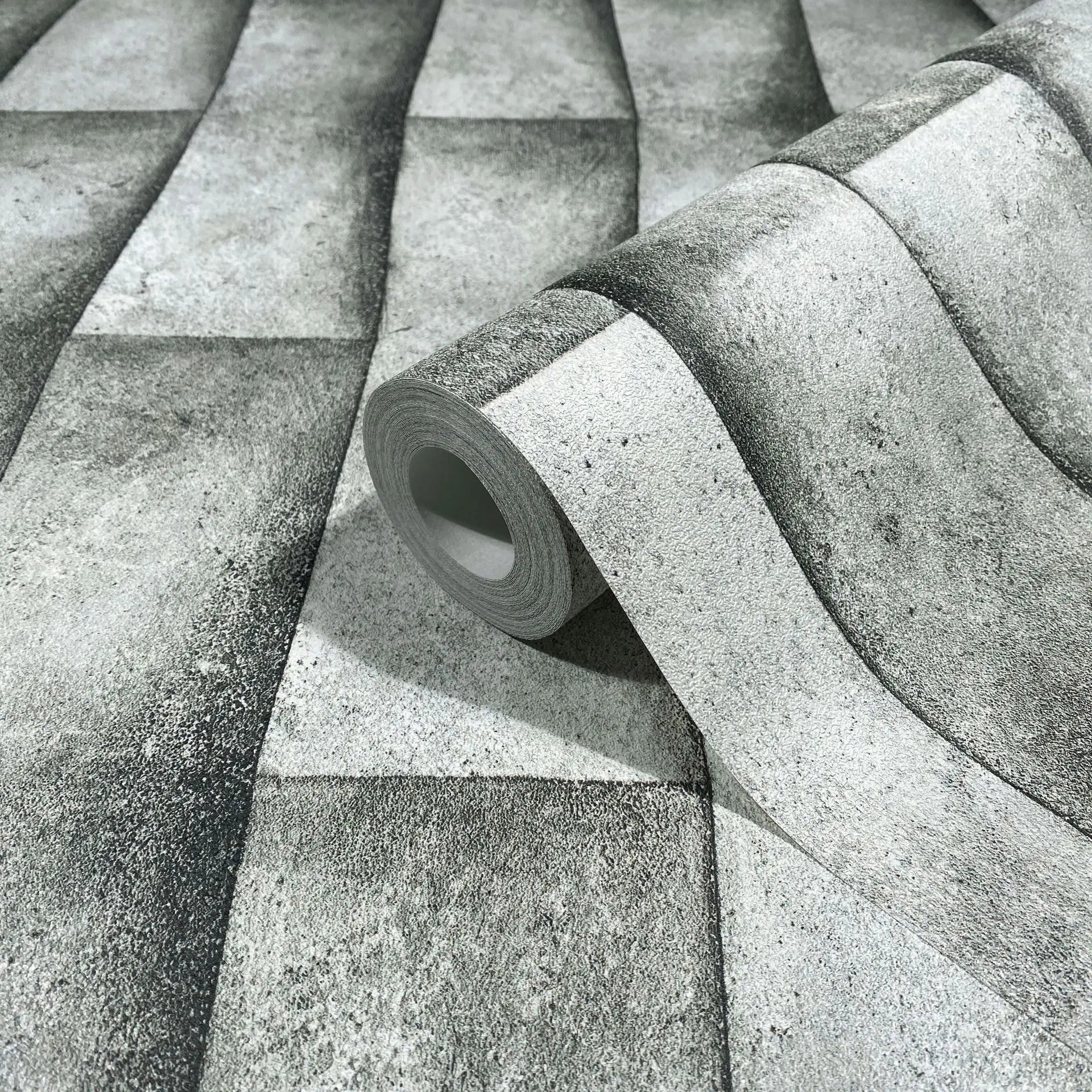 Marburg Novamur Mona 81651 Gray wallpaper roll on a matching unrolled sheet, showing a concrete-textured design with broad wavy bands and shaded blocks.