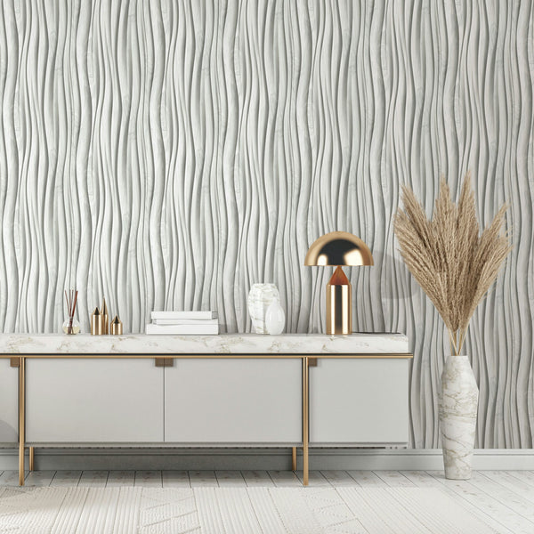 Marburg Novamur Mona 81669 Grey and white wallpaper with vertical wavy stripes, shown behind a console topped with a gold dome lamp and decor, next to a tall vase of pampas grass.