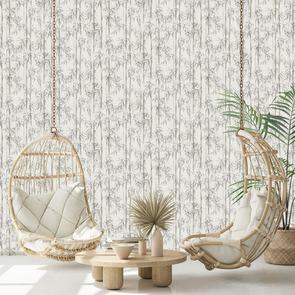 Marburg Novamur Mona 81671 Gray bamboo pattern wallpaper on a light background shown behind two rattan hanging chairs with cushions, a low round wooden table with decorative vases and a bowl, and a potted palm in a woven basket.
