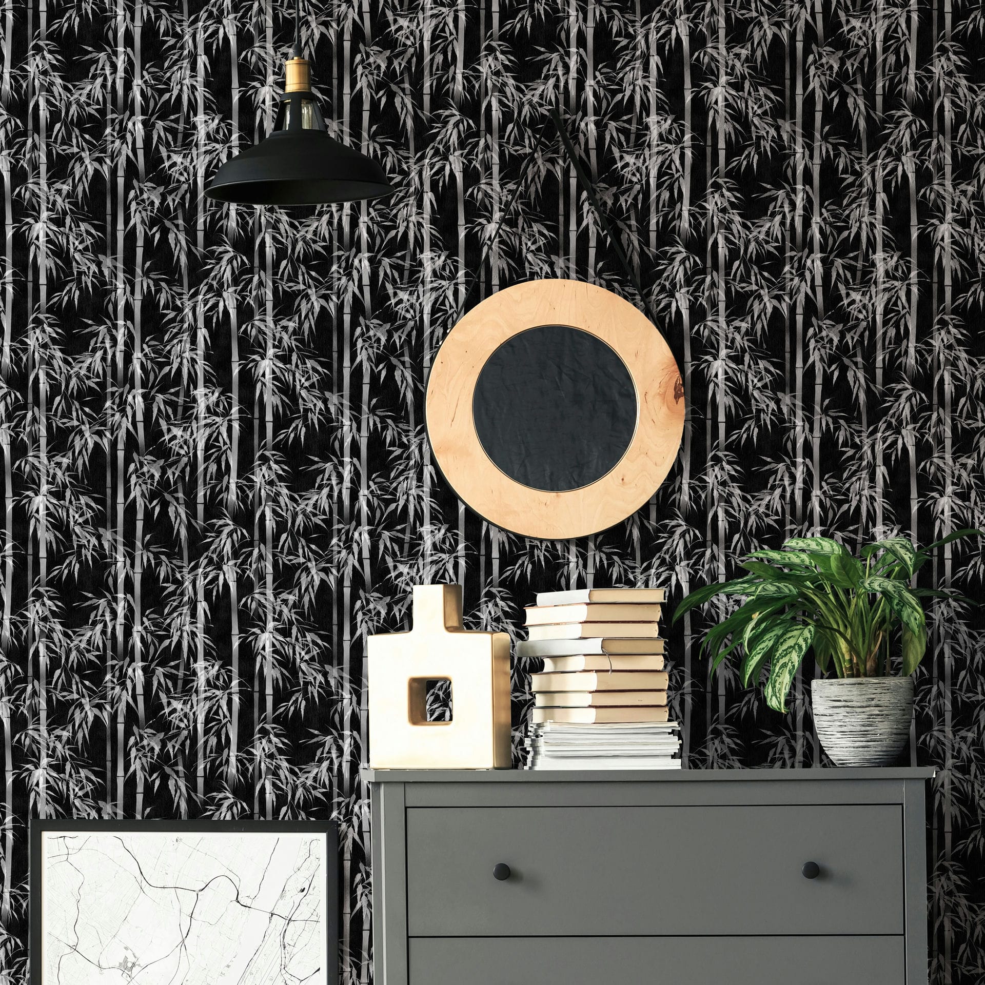 Marburg Novamur Mona 81672 Black-and-white bamboo wallpaper behind a grey dresser with stacked books, a decorative object, a potted plant, a round wood-framed mirror, a pendant light, and a framed print.