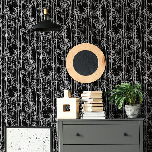 Marburg Novamur Mona 81672 Black-and-white bamboo wallpaper behind a grey dresser with stacked books, a decorative object, a potted plant, a round wood-framed mirror, a pendant light, and a framed print.