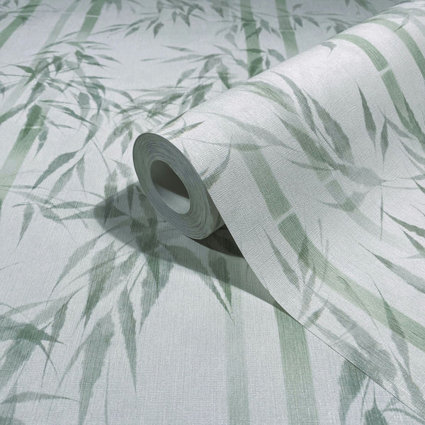 Marburg Novamur Mona 81674 Close-up of a wallpaper roll with a green bamboo stalks and leaves pattern on a light textured background, partially unrolled on a matching surface.