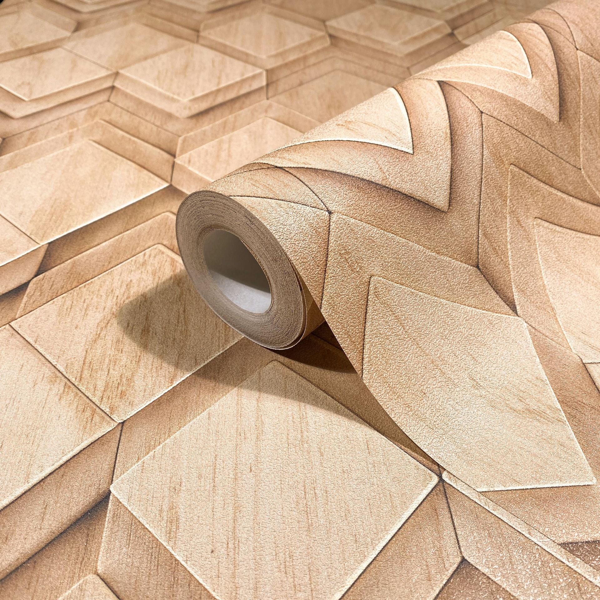 Marburg Novamur Mona 81676 Wallpaper roll on matching surface showing a beige and brown 3D geometric pattern with layered squares and chevron shapes and a subtle woodgrain effect.