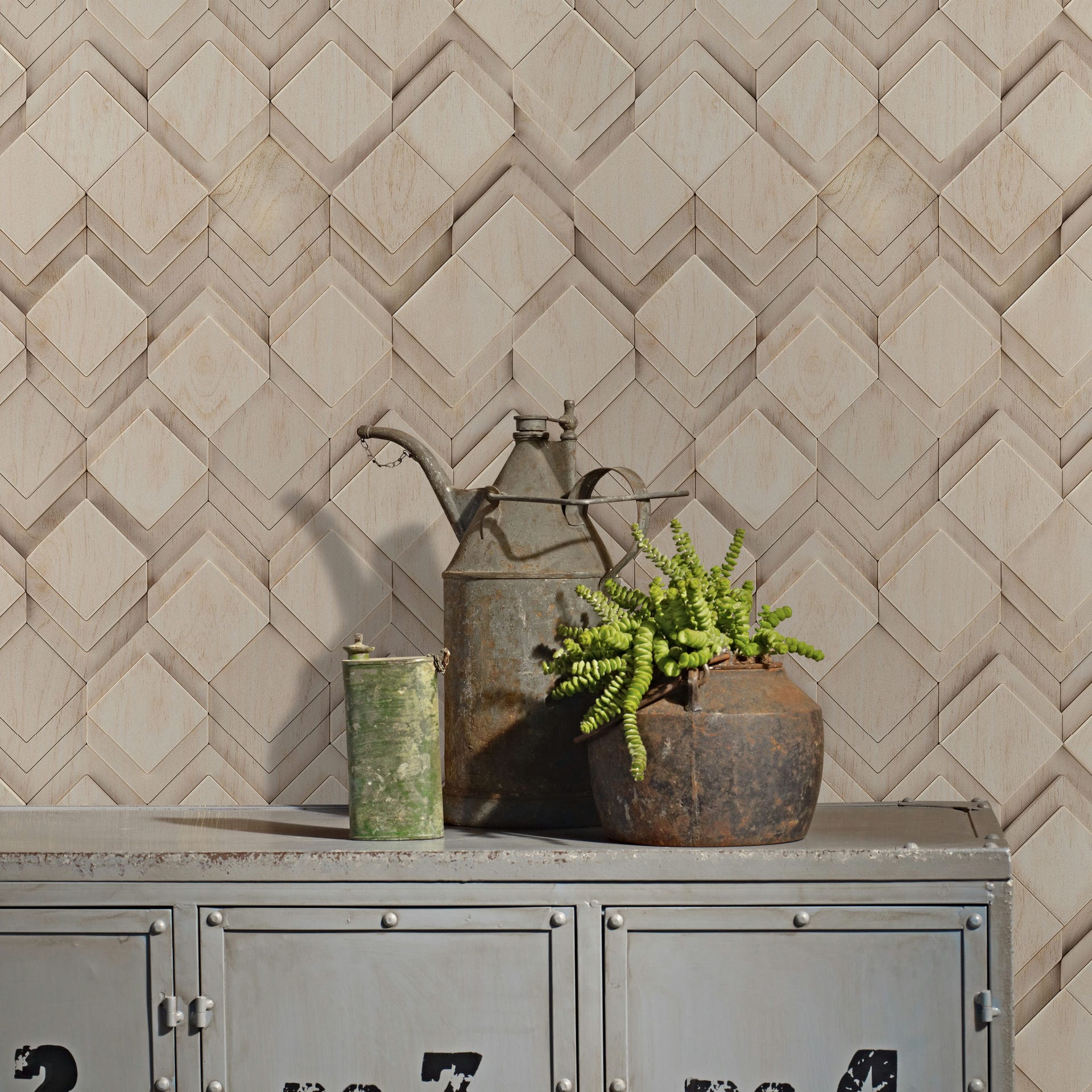 Marburg Novamur Mona 81677 Beige and grey geometric wallpaper with a layered diamond chevron pattern and subtle wood‑grain effect; in front, a metal cabinet holds a rusty watering can, a small green canister, and a potted succulent.
