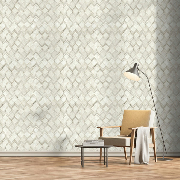 Marburg Novamur Mona 81679 Light grey and white geometric chevron-and-diamond wallpaper shown in a styled room scene with an armchair, a floor lamp, a low round table with books, and a wood herringbone floor.
