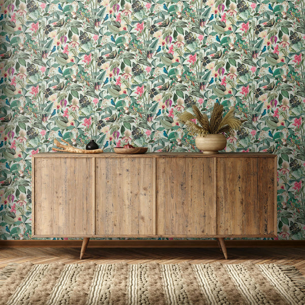 Marburg Novamur Mona 81684 Dense botanical print with green leaves, pink flowers, and small birds on a light background wallpaper on a living room feature wall.