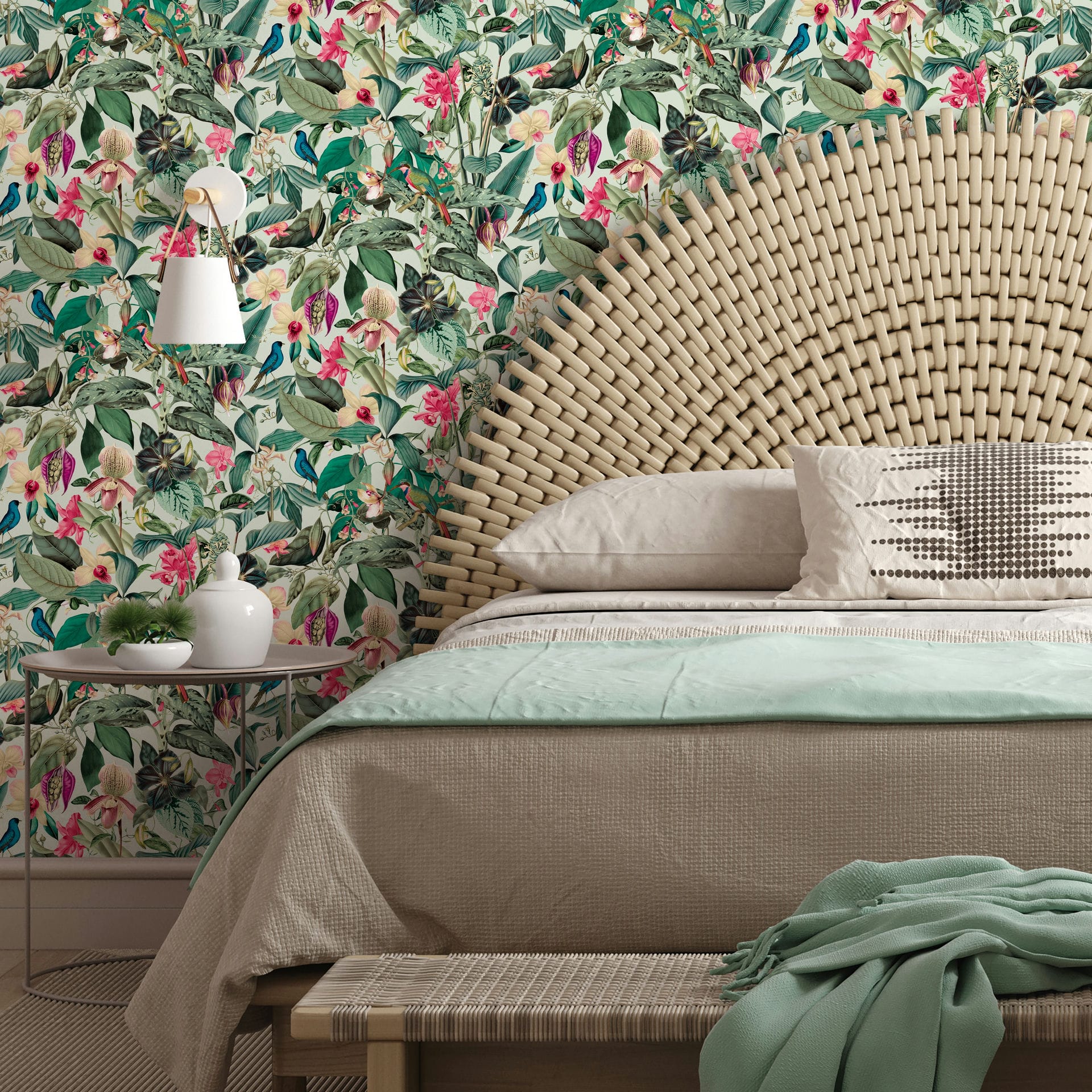 Marburg Novamur Mona 81684 Tropical floral and leaf wallpaper with small birds on a light background behind a bed with a woven arched headboard, wall sconce, and small side table with decor.
