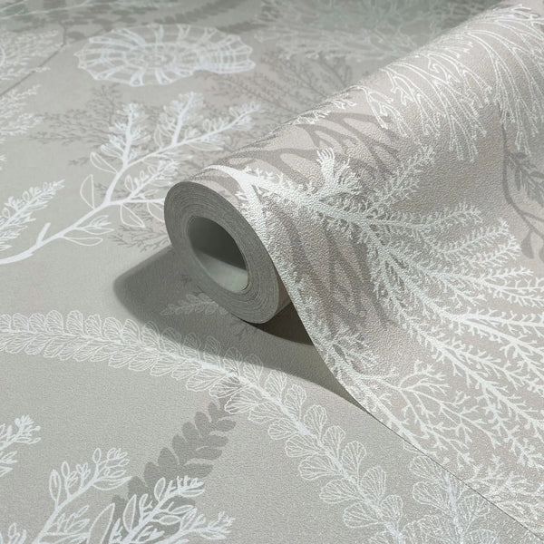 Marburg Novamur Mona 81690 Close-up of a partially unrolled wallpaper roll on a matching surface, showing a beige background with white botanical fronds and leaf motifs.