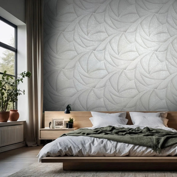 Marburg Ritus 35501 Abstract swirl-pattern wallpaper in light gray tones covers a bedroom feature wall behind a low wooden bed, with a window, curtain, and potted plants to the side.