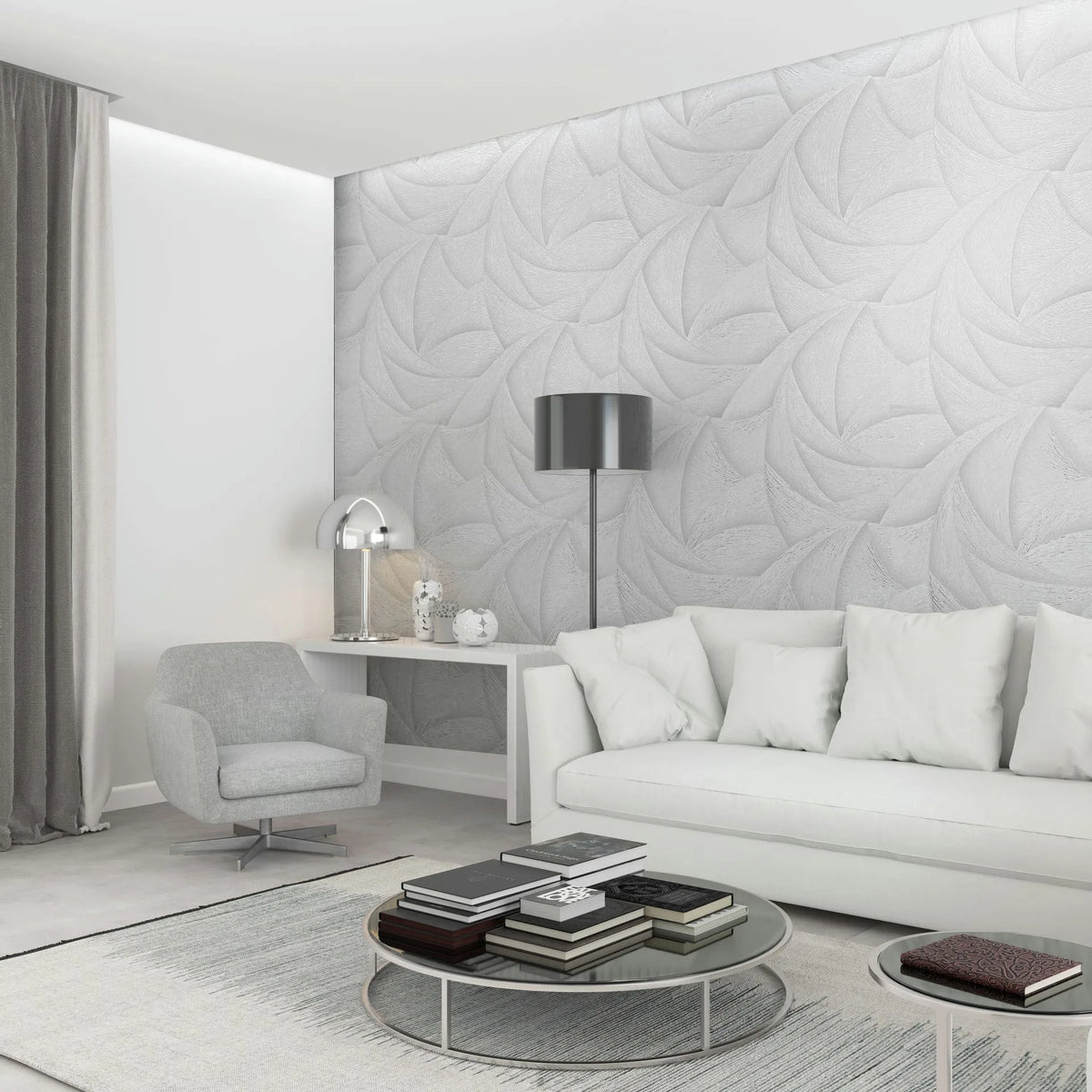 Marburg Ritus 35503 Living room scene with a light grey-white wallpaper featuring large overlapping swirl motifs used as a feature wall behind a white sofa. Round coffee tables with books, an armchair, a floor lamp, a console with a dome table lamp, curtains, and a rug are also,.