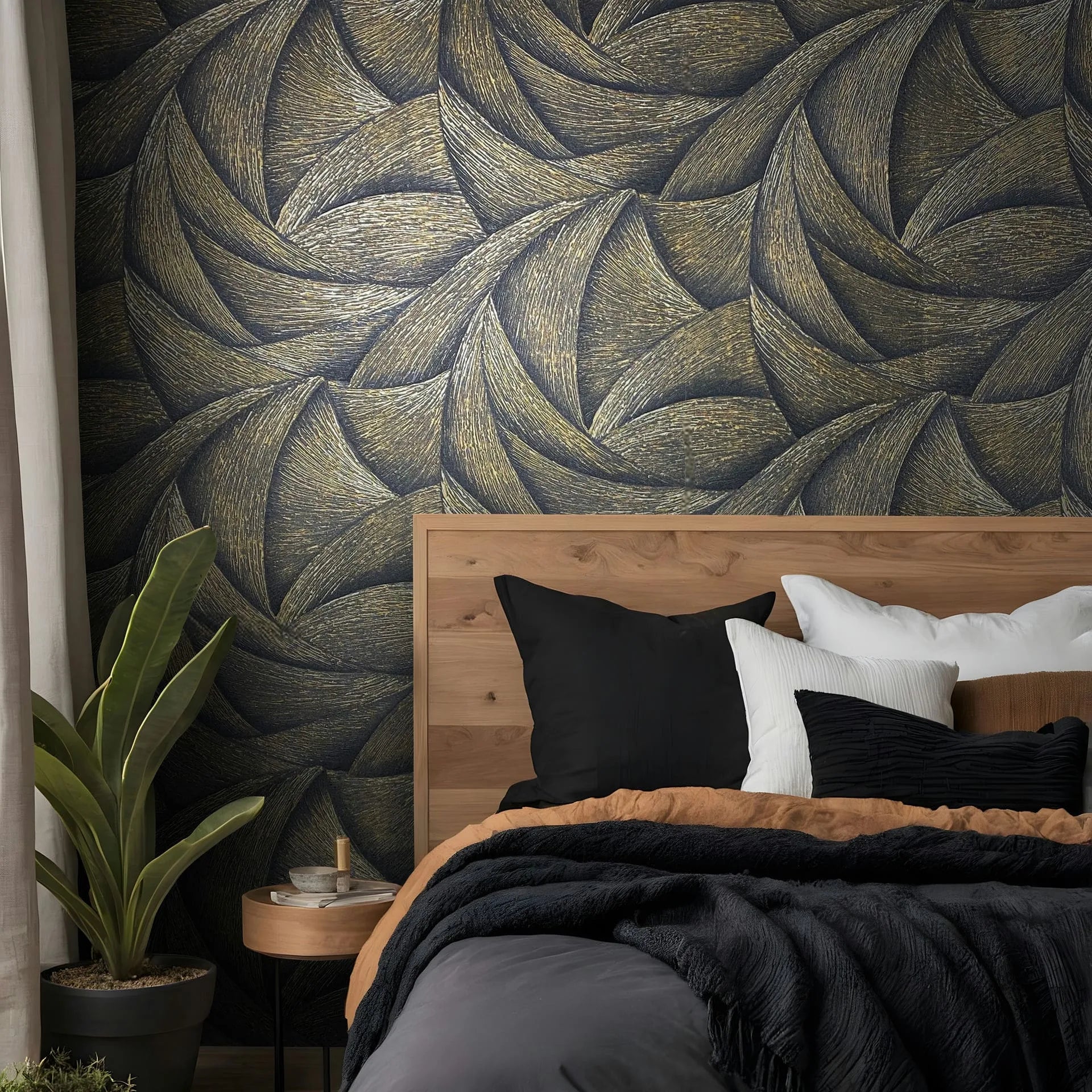 Marburg Ritus 35506 Black and gold wallpaper with a large interlocking leaf-like pattern behind a wooden bed, with pillows, bedding, a round nightstand, and a potted plant visible.