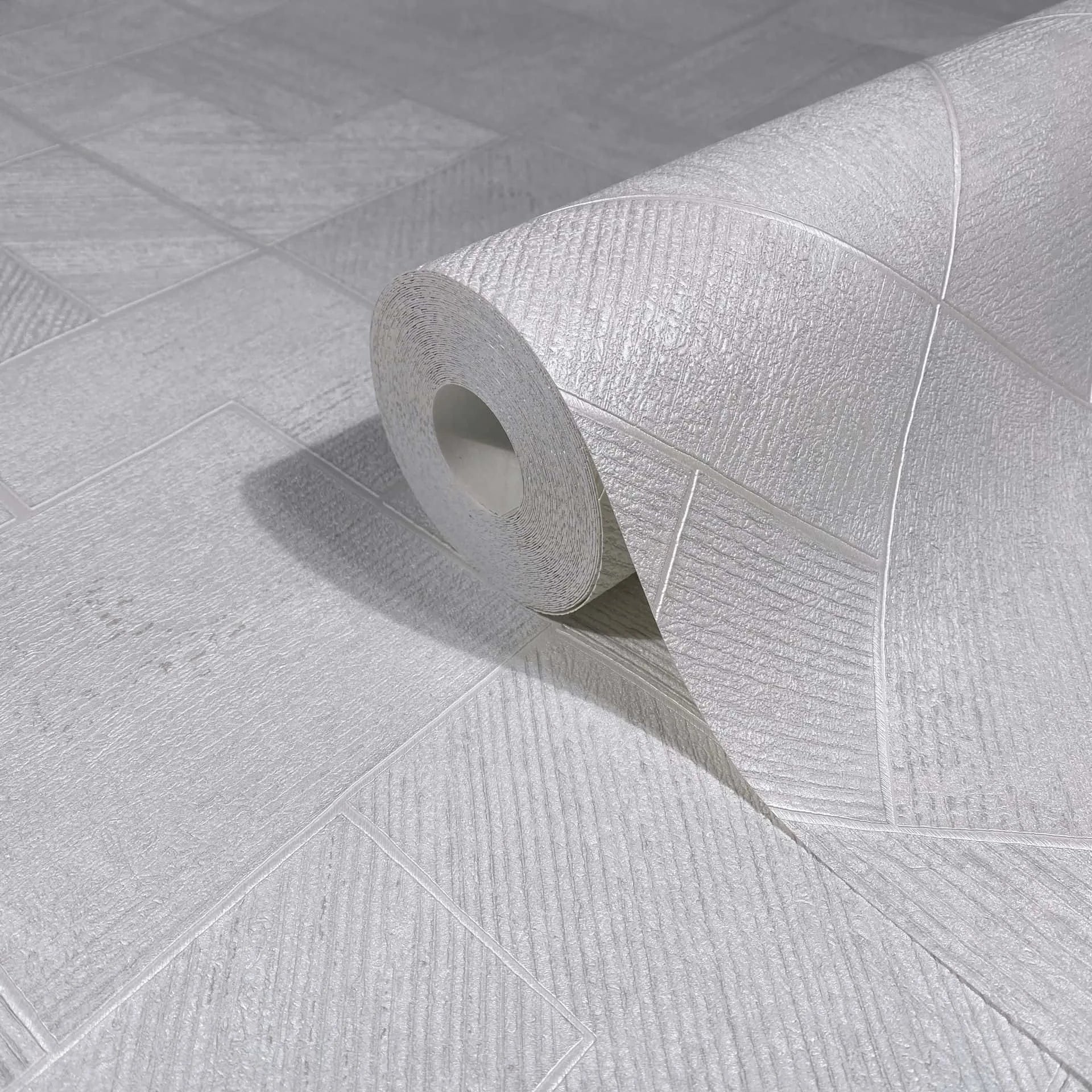 Marburg Ritus 35508 Close-up of a white textured wallpaper roll resting on matching surface with geometric rectangular panels and diagonal striations.