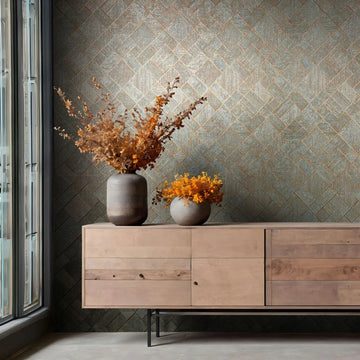 Marburg Ritus 35512 Geometric wallpaper with a blue background and copper diagonal grid behind a wood sideboard. Two vases with dried foliage sit on the cabinet next to a tall window.