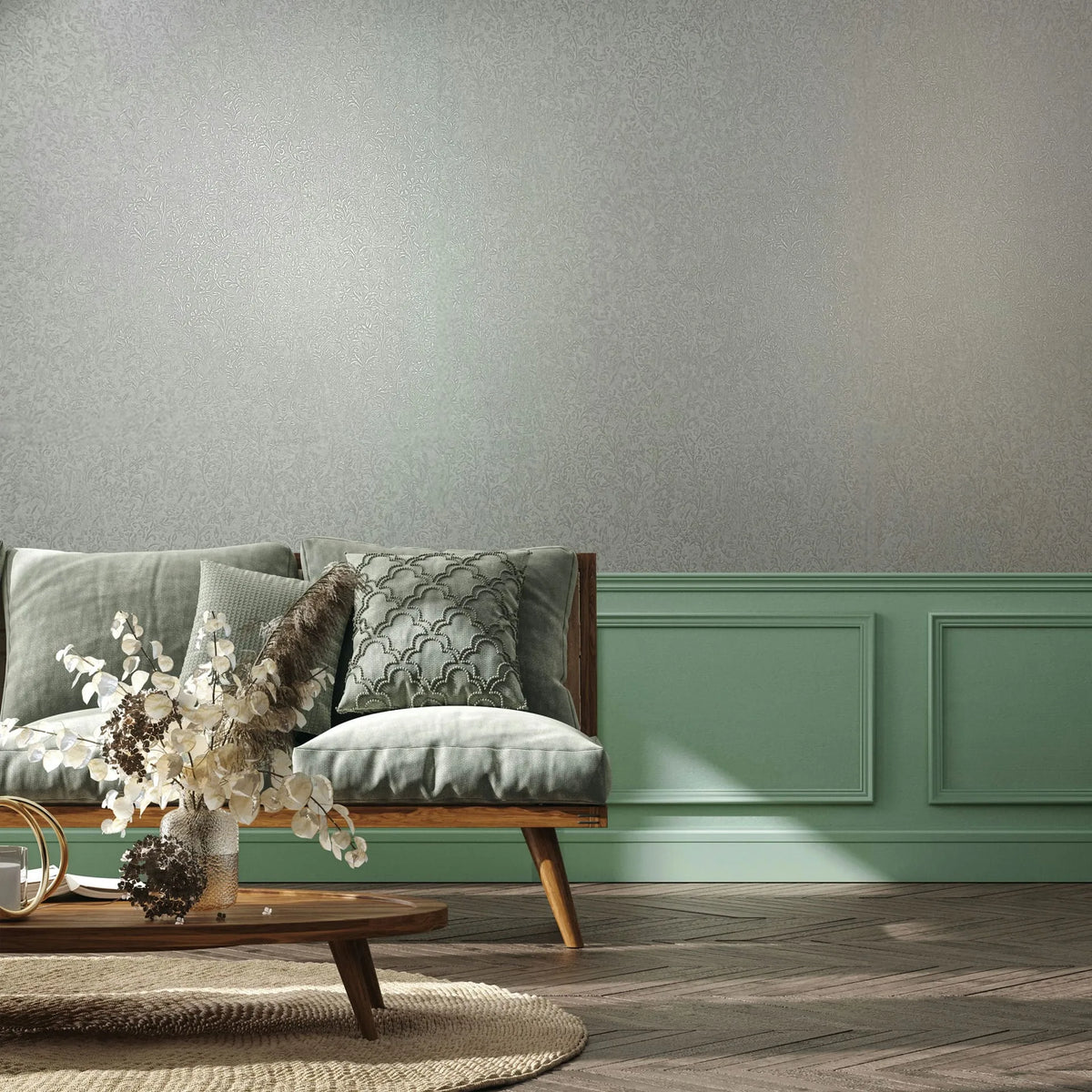 Marburg Ritus 35529 Light gray wallpaper with a subtle allover ornamental pattern, shown in a living room above mint green paneled wainscoting with a wooden sofa and a low coffee table holding a vase of dried flowers.