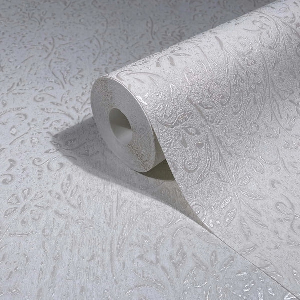Marburg Ritus 35530 White textured wallpaper roll partially unrolled on a matching surface, showing a raised scroll and leaf pattern.