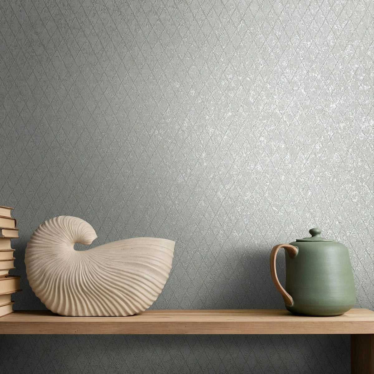 Marburg Ritus 35536 Gray diamond-patterned wallpaper shown behind a wooden shelf with stacked books, a shell-shaped sculpture, and a lidded green ceramic jug.