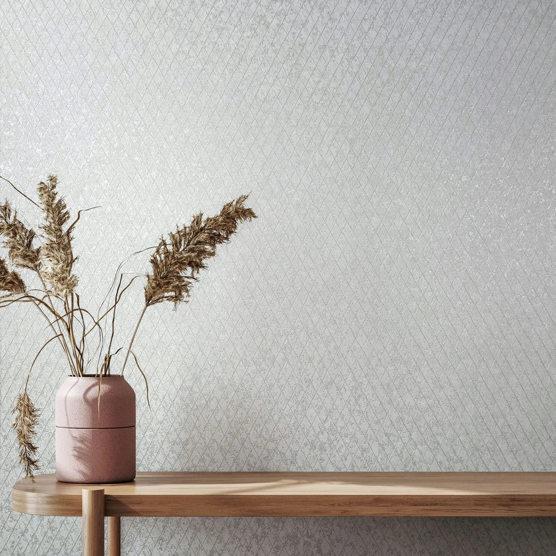 Marburg Ritus 35537 Light grey-white wallpaper with a small diagonal diamond pattern behind a wooden console holding a pink vase with dried grasses.