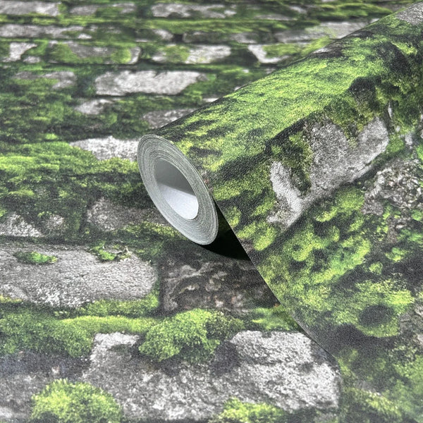 Marburg Struktura 45731 Wallpaper roll on matching surface showing a gray stone wall pattern with bright green moss details.