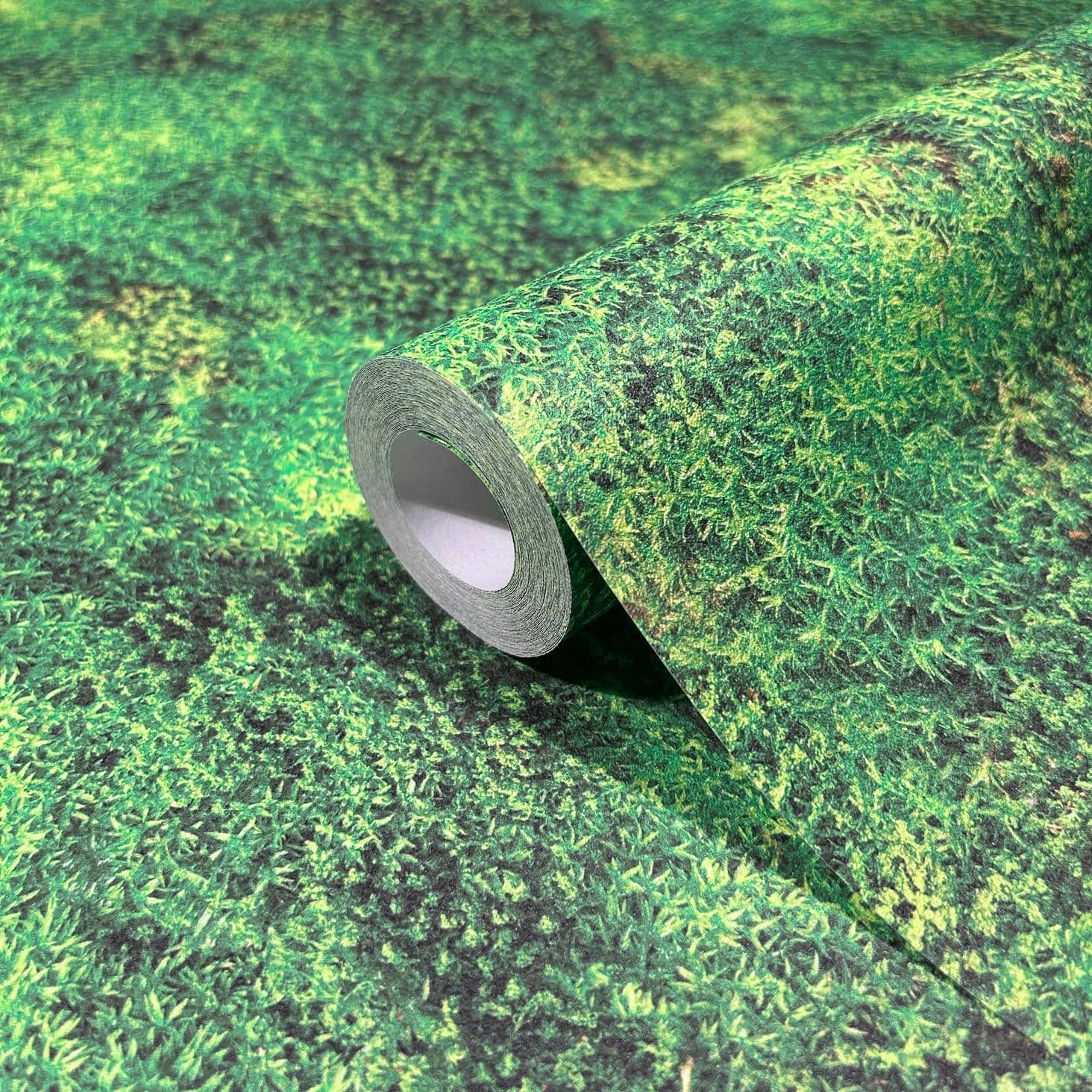 Marburg Struktura 45733 Close-up of a wallpaper roll with a dense green foliage-texture pattern resting on the matching unrolled wallpaper.