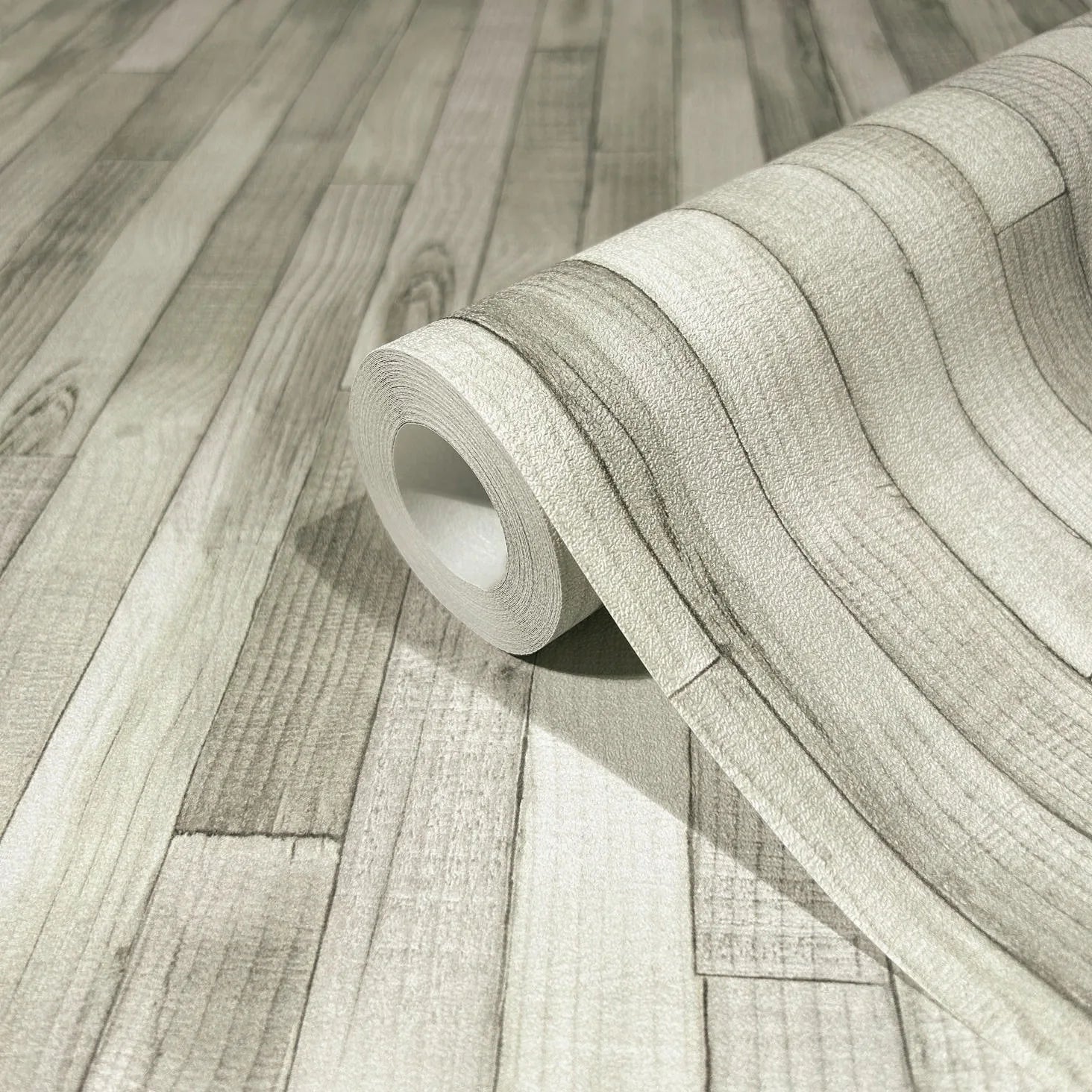 Marburg Struktura 45735 Close-up of a wallpaper roll on a matching surface showing a light gray faux wood plank design with grain and plank lines.