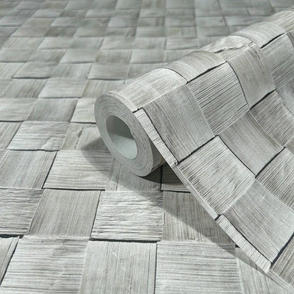 Marburg Struktura 45741 A wallpaper roll rests on matching gray wallpaper featuring a woven square pattern with fine linear texture.
