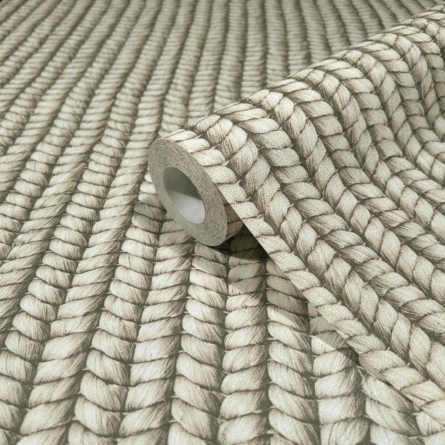 Marburg Struktura 45748 A wallpaper roll resting on matching unrolled wallpaper featuring vertical rows of a braided rope design in beige and gray tones.