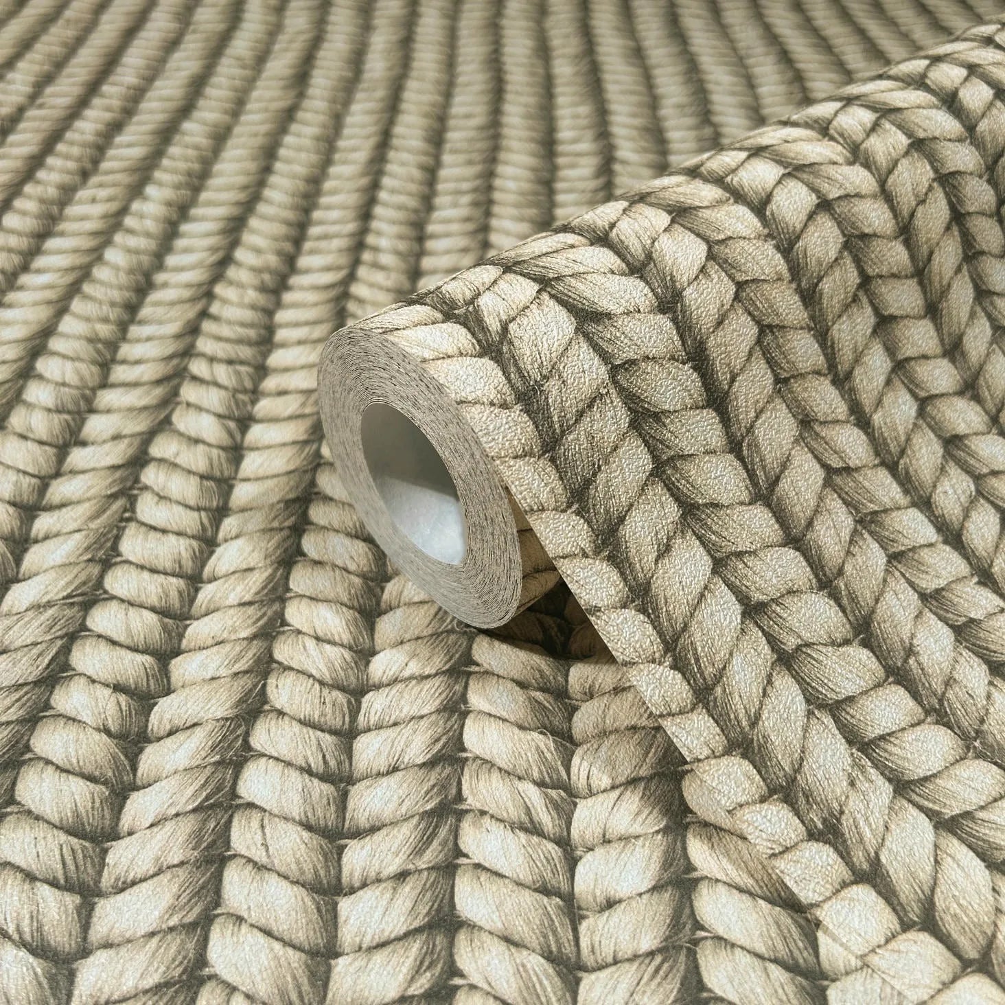 Marburg Struktura 45749 Close-up of a wallpaper roll showing a beige braided rope design with shaded, textured effect, resting on matching unrolled wallpaper.