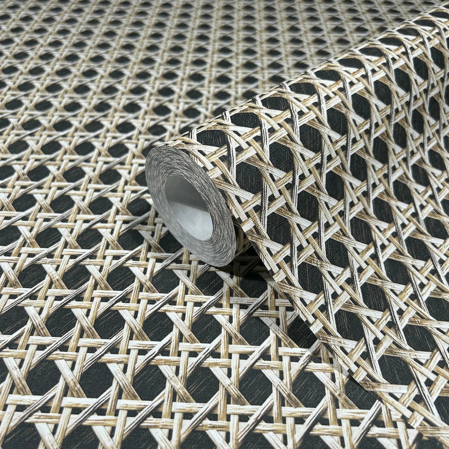 Marburg Struktura 45751 Close-up of a wallpaper roll featuring a beige and brown woven cane lattice pattern on a dark background, displayed on an unrolled sheet of the same design.