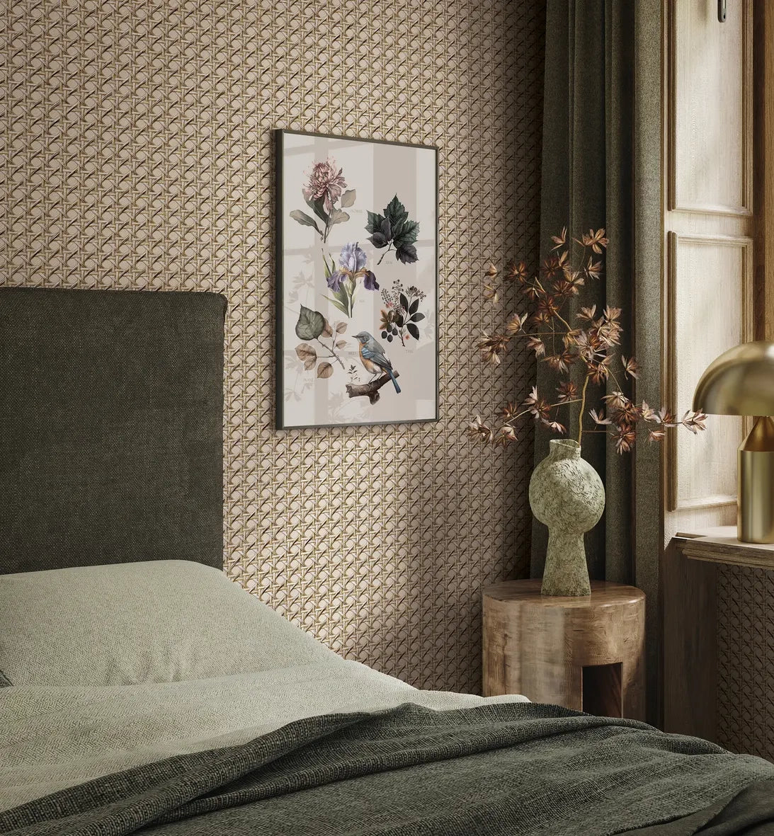 Marburg Struktura 45752 Bedroom scene with beige geometric patterned wallpaper behind a dark upholstered headboard. A framed botanical print hangs on the wall beside a window with curtains, a round wooden side table holds a sculptural vase with branches, and a brass lamp sits on the窓.