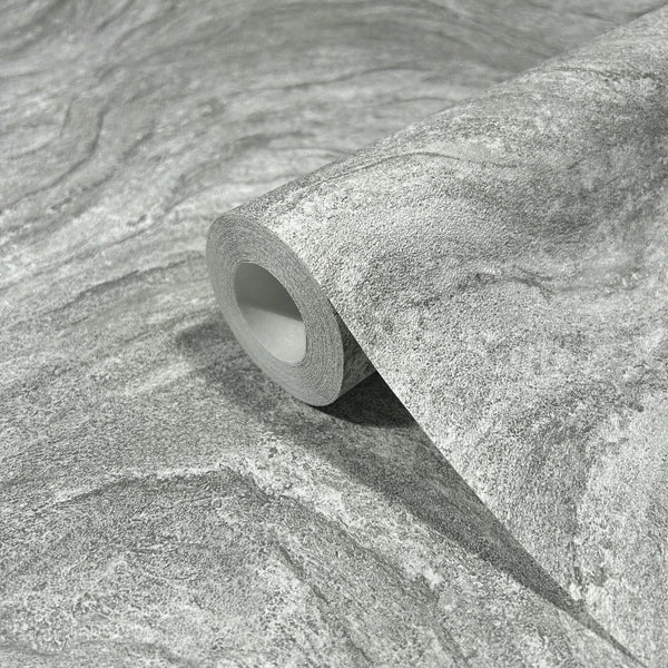 Marburg Struktura 45758 Close-up of a gray stone-effect wallpaper roll resting on a matching unrolled sheet, showing fine grain and gentle wavy veining.