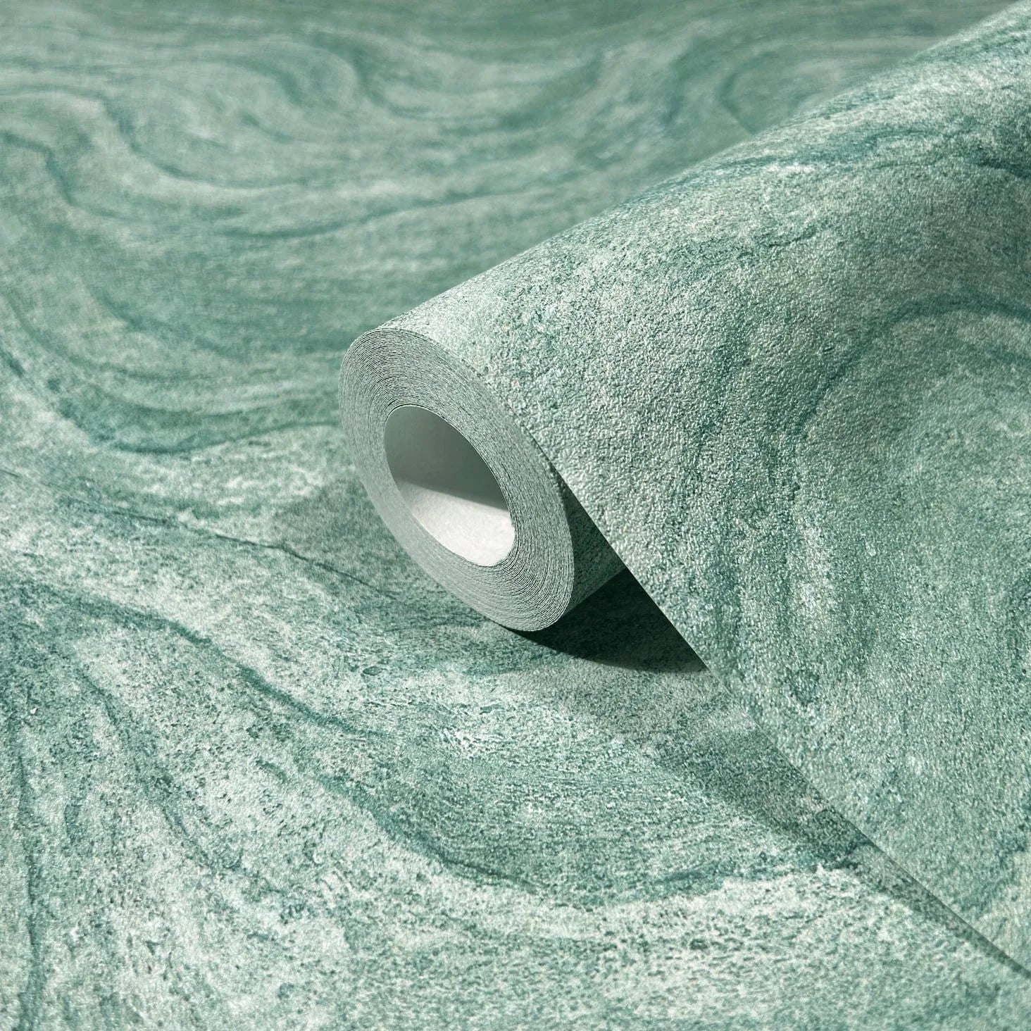 Marburg Struktura 45759 Close-up of a green swirl-textured wallpaper roll resting on a matching unrolled sheet.