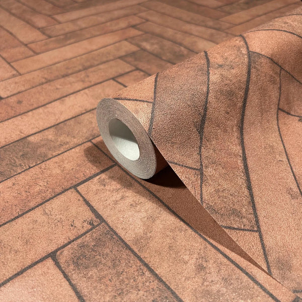 Marburg Struktura 45763 Close-up of a wallpaper roll resting on matching unrolled wallpaper, showing a faux brick pattern of rectangular blocks with dark grout lines in warm brown tones.