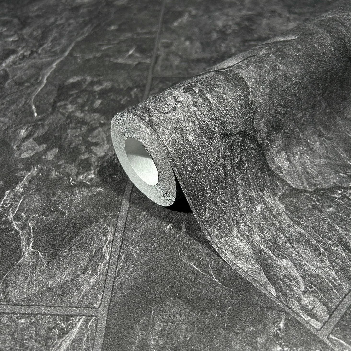 Marburg Struktura 45765 A wallpaper roll on an unrolled sheet showing a dark anthracite stone tile effect with veined slate texture and grout lines.