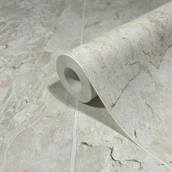 Marburg Struktura 45768 Close-up of a wallpaper roll resting on matching beige stone‑effect wallpaper with subtle veining.