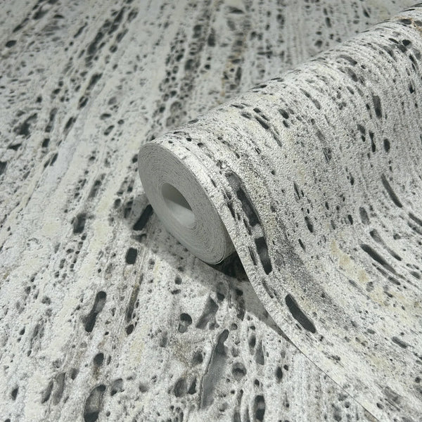Marburg Travertino 33350 Close-up of a partially unrolled wallpaper roll showing a beige and gray stone-effect, pitted texture pattern.