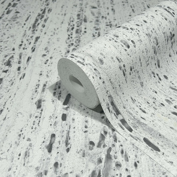 Marburg Travertino 33352 A wallpaper roll partially unrolled on matching material, showing a gray and white travertine stone–look pattern with irregular streaks and pits.