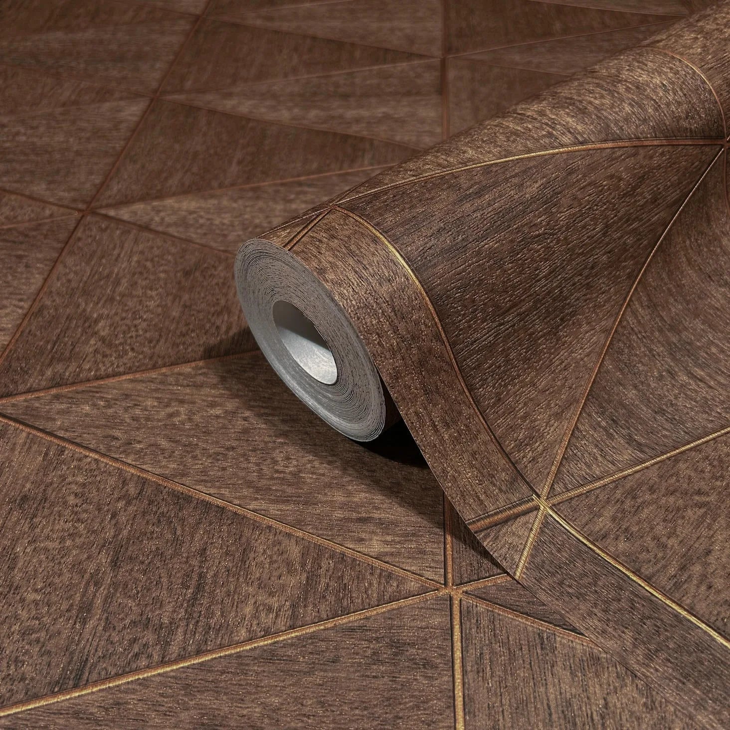 Marburg Travertino 33361 Close-up of a brown geometric wallpaper roll with thin gold-toned lines forming triangles, shown on a matching unrolled sheet.