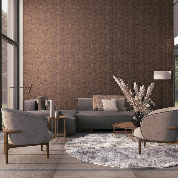 Marburg Travertino 33361 Brown geometric wallpaper with interlocking triangles shown in a modern living room featuring a gray sofa, two armchairs, a round rug, coffee table, side table, floor lamp, wall sconce, large window, and a vase with dried grasses.