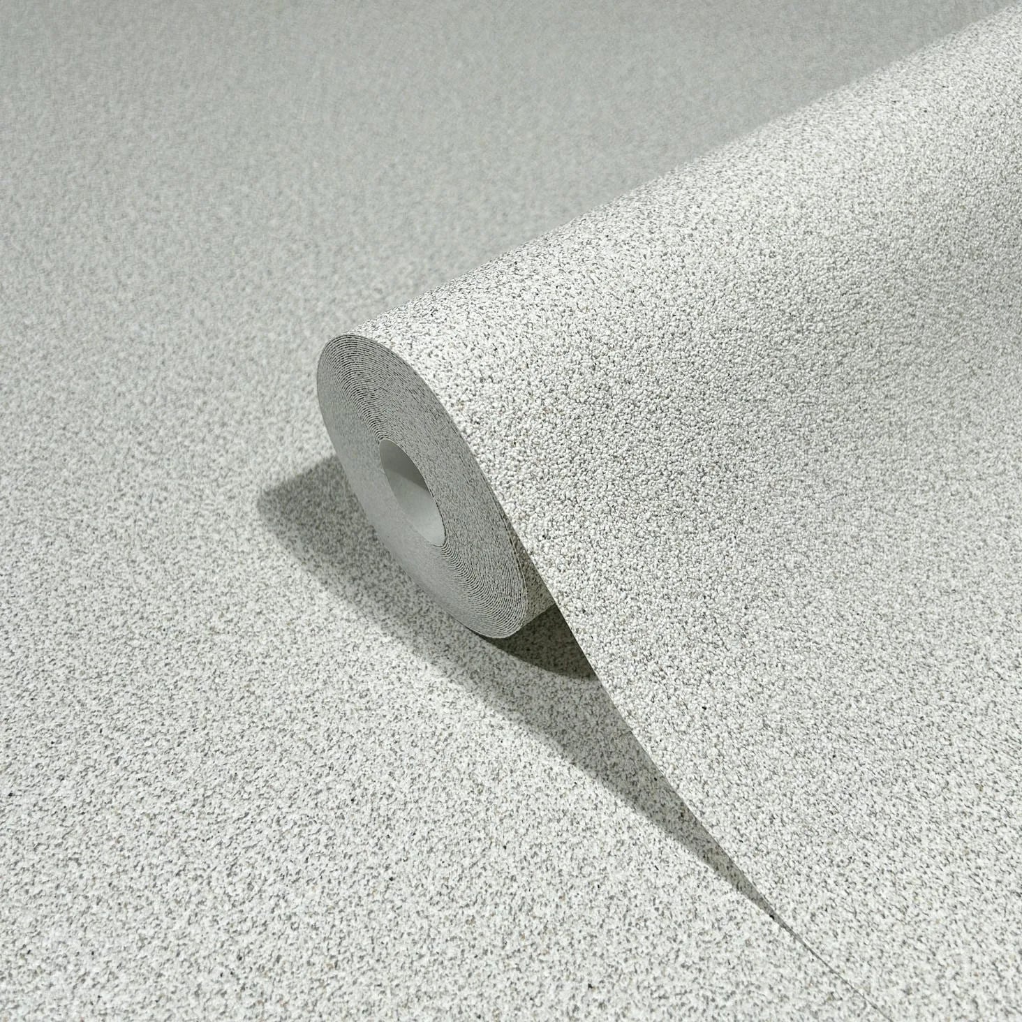 Marburg Travertino 33362 A wallpaper roll with a light gray and beige speckled texture, partially unrolled on a matching surface.