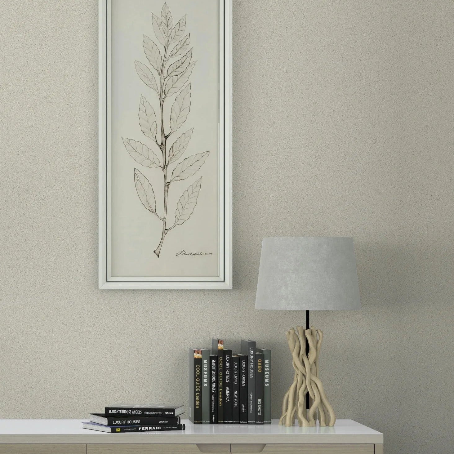 Marburg Travertino 33363 Light beige textured wallpaper behind a modern sideboard styled with stacked books, a sculptural table lamp, and a tall framed leaf illustration.