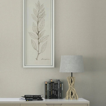 Marburg Travertino 33363 Light beige textured wallpaper behind a modern sideboard styled with stacked books, a sculptural table lamp, and a tall framed leaf illustration.